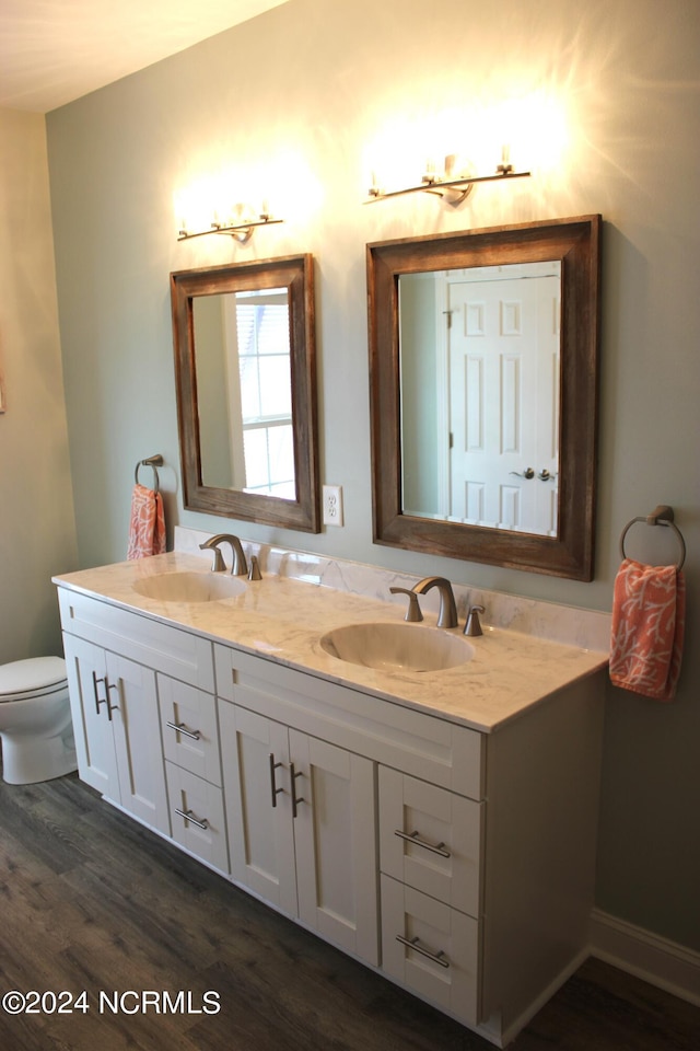 bathroom featuring dual vanity, toilet, and hardwood / wood-style floors