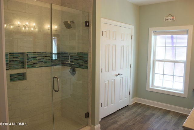 bathroom featuring a shower with door, a wealth of natural light, and hardwood / wood-style flooring