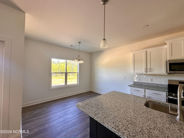 kitchen featuring baseboards, stainless steel microwave, light stone counters, white cabinetry, and backsplash