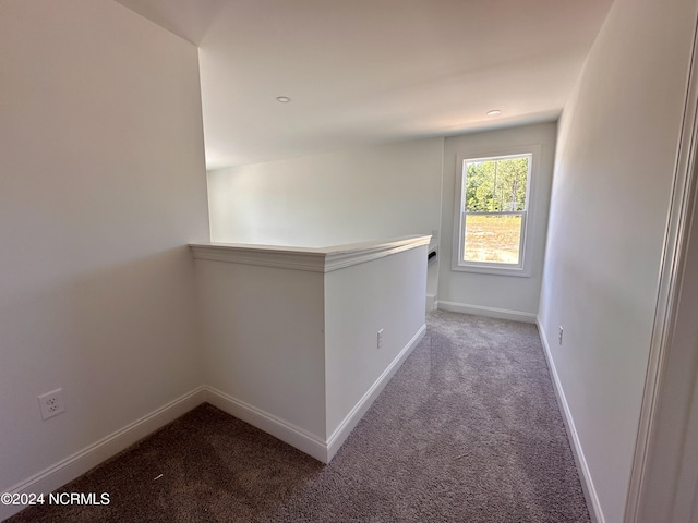 hallway with carpet, an upstairs landing, and baseboards