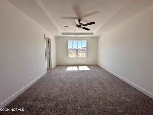 unfurnished room with ceiling fan, a raised ceiling, light colored carpet, and baseboards