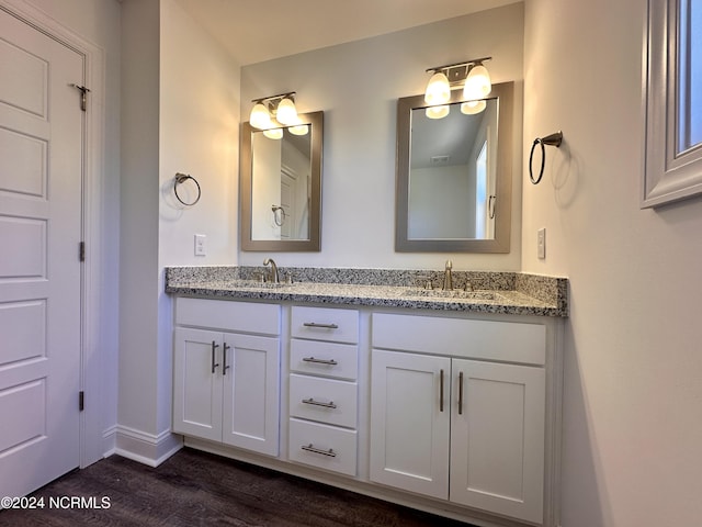 bathroom with wood finished floors, a sink, baseboards, and double vanity