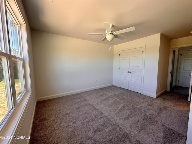 unfurnished bedroom with carpet, baseboards, ceiling fan, and a closet