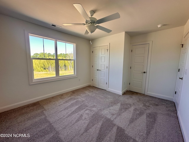 unfurnished bedroom featuring carpet floors, visible vents, baseboards, and a ceiling fan