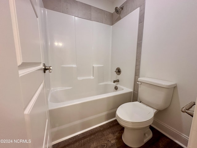 bathroom with washtub / shower combination, baseboards, and toilet