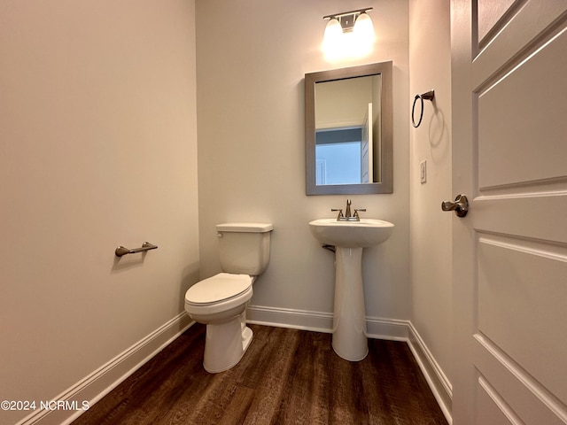 bathroom featuring toilet, a sink, baseboards, and wood finished floors