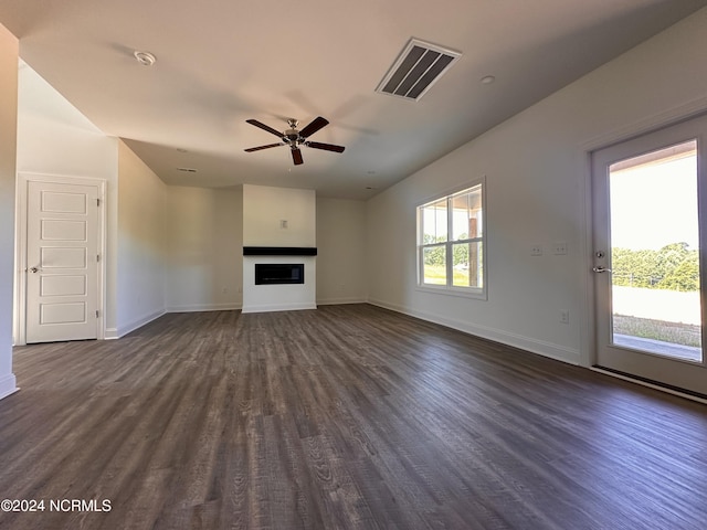 unfurnished living room with baseboards, visible vents, dark wood finished floors, and a fireplace