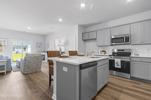 kitchen with appliances with stainless steel finishes, a sink, gray cabinetry, and wood finished floors