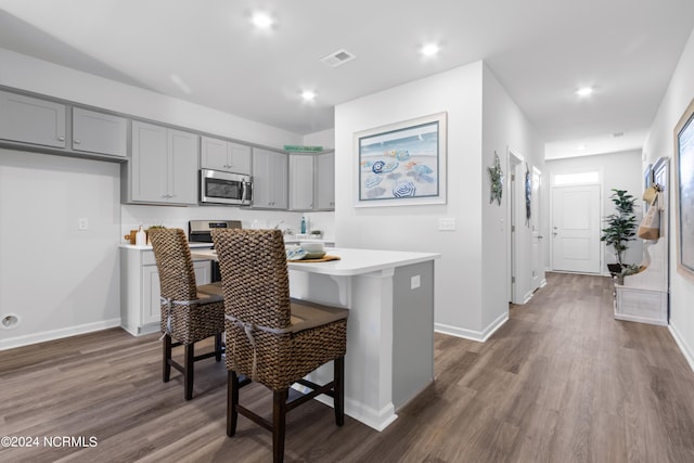 kitchen with light countertops, gray cabinets, stainless steel microwave, and visible vents