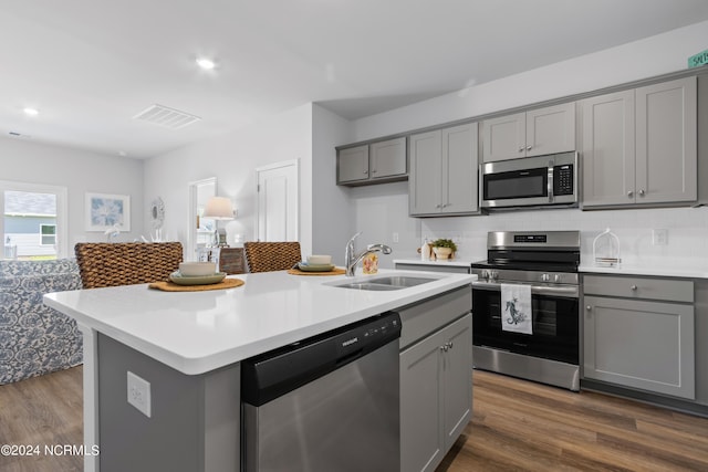 kitchen featuring appliances with stainless steel finishes, dark wood-type flooring, gray cabinets, light countertops, and a sink