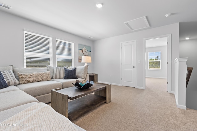 living room featuring attic access, light colored carpet, visible vents, and baseboards