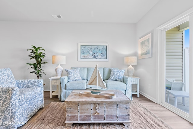 living area featuring baseboards, visible vents, and wood finished floors