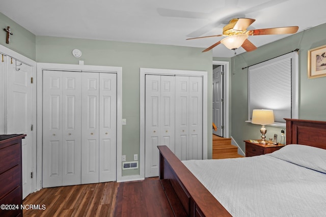 bedroom with ceiling fan, dark wood-type flooring, and multiple closets