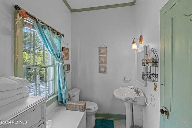 bathroom featuring a wealth of natural light, toilet, ornamental molding, and tile patterned flooring