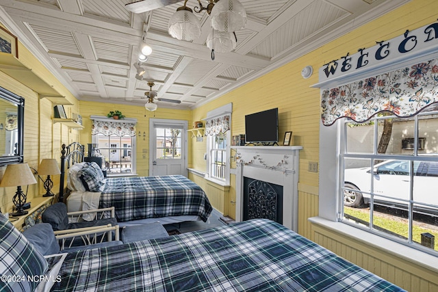 bedroom featuring ceiling fan, multiple windows, crown molding, and wooden walls