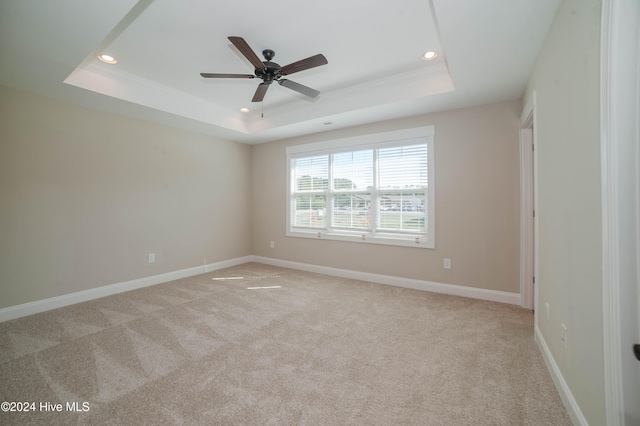 carpeted spare room with ornamental molding, a tray ceiling, and ceiling fan