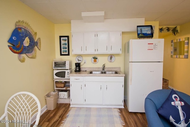 kitchen with white cabinets, white appliances, sink, and hardwood / wood-style flooring