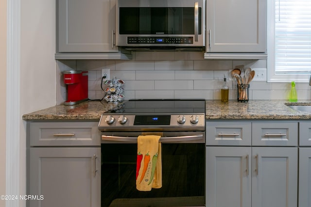 kitchen featuring stainless steel appliances, sink, backsplash, and light stone counters