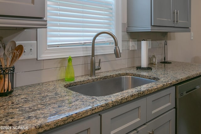 kitchen featuring sink, gray cabinets, dishwasher, stone counters, and tasteful backsplash