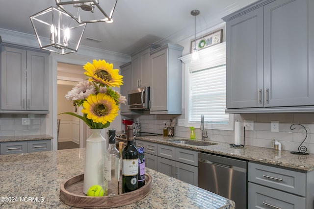 kitchen with pendant lighting, sink, stainless steel appliances, and light stone countertops