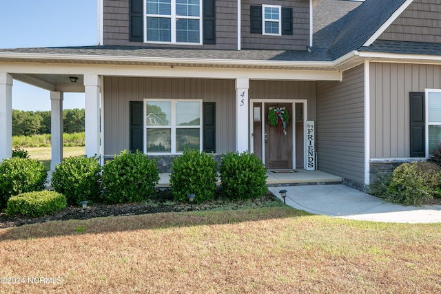 view of exterior entry with a yard and covered porch