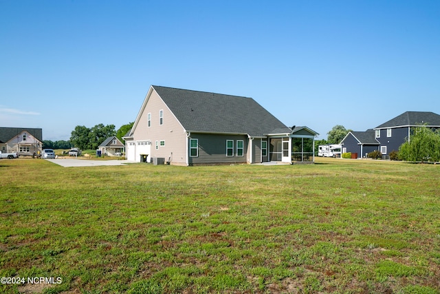 back of property with central AC, a garage, a sunroom, and a lawn