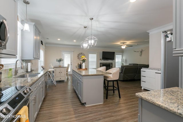 kitchen with sink, hanging light fixtures, ornamental molding, gray cabinets, and a kitchen island