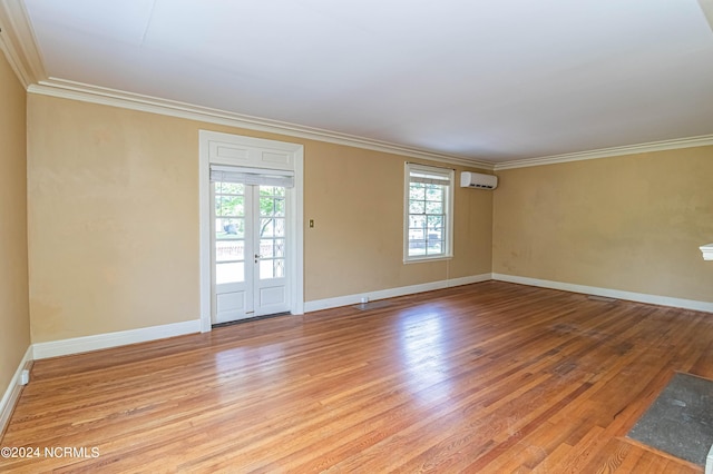 empty room with light hardwood / wood-style floors, french doors, ornamental molding, and an AC wall unit