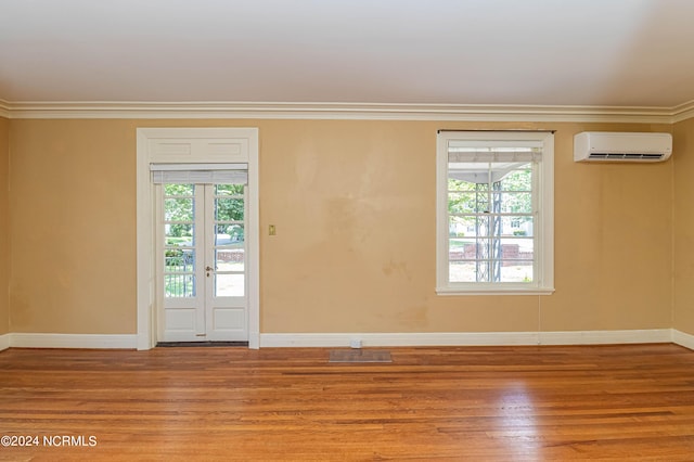 empty room featuring crown molding, hardwood / wood-style floors, and a wall mounted AC