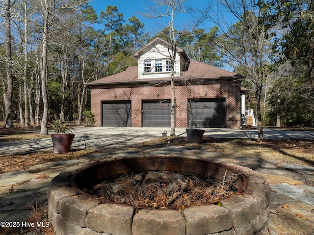 view of side of property with a garage, brick siding, driveway, and roof with shingles