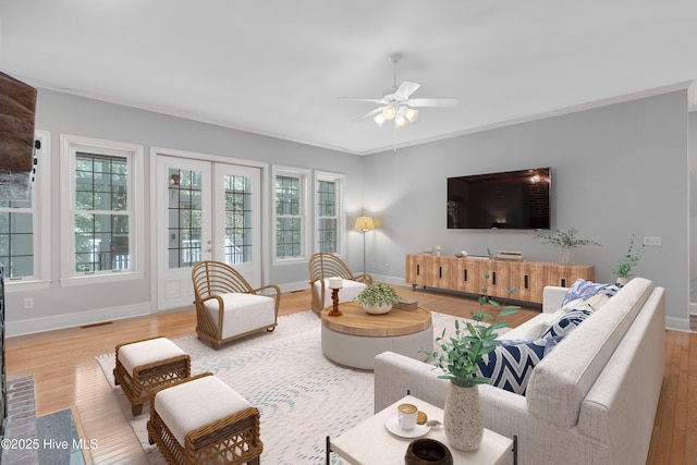 living area with french doors, plenty of natural light, wood finished floors, and a ceiling fan