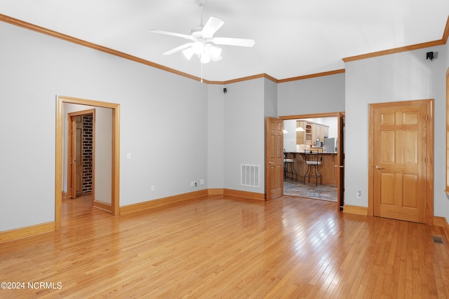 interior space with visible vents, baseboards, ceiling fan, light wood-type flooring, and ornamental molding