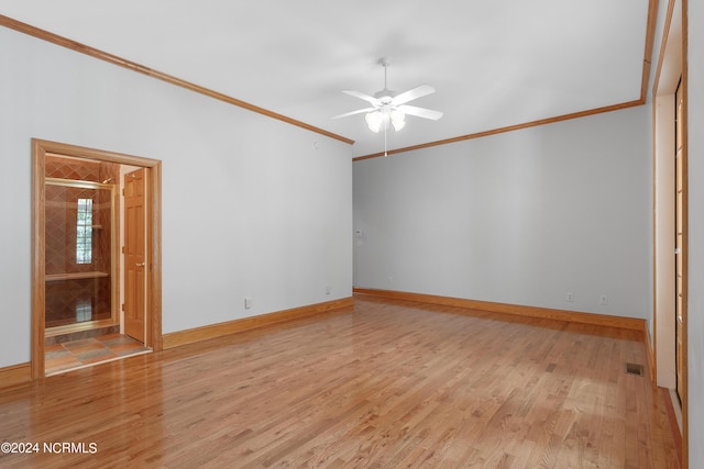 spare room featuring baseboards, visible vents, ceiling fan, ornamental molding, and light wood-type flooring