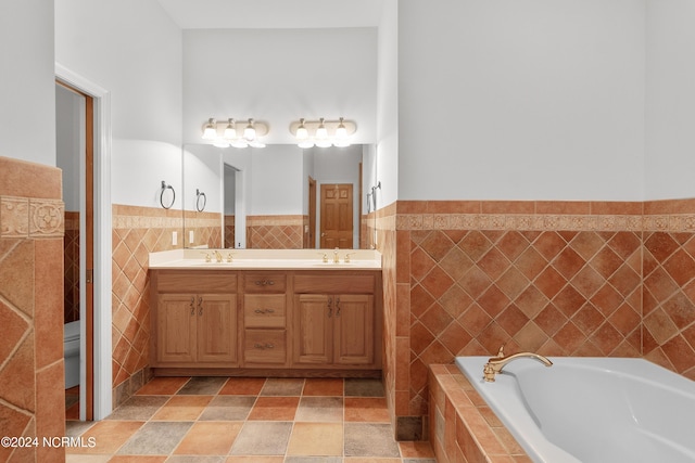 full bathroom with double vanity, tile walls, a bath, and a sink