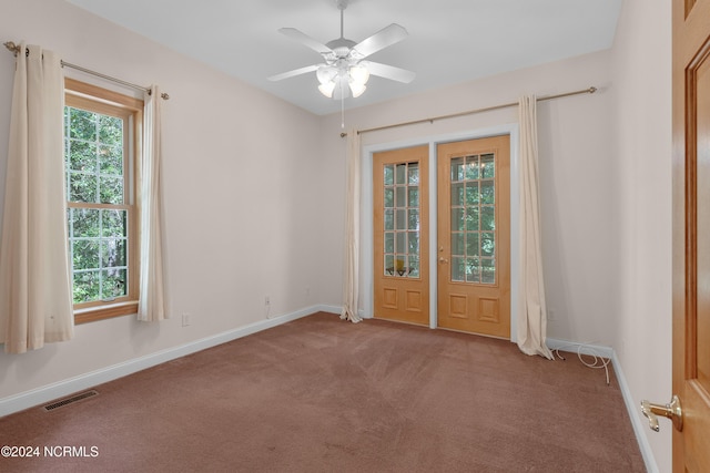 empty room featuring visible vents, carpet flooring, baseboards, and ceiling fan