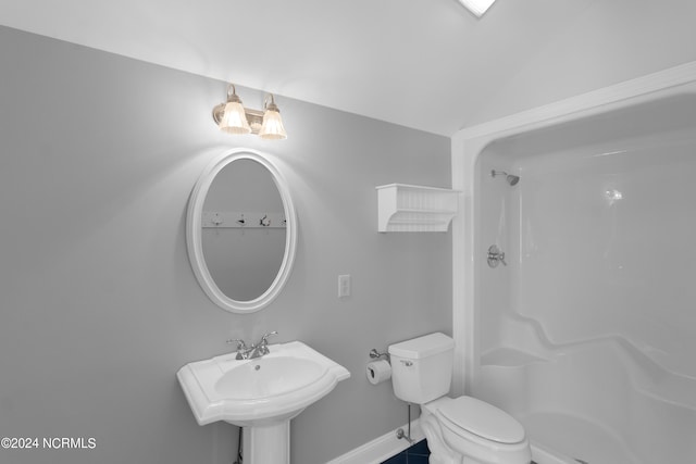 bathroom with tile patterned floors, walk in shower, sink, toilet, and lofted ceiling