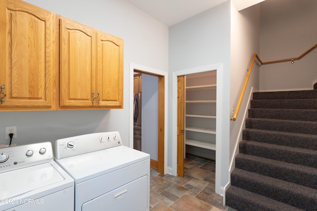 laundry room featuring stone finish floor, cabinet space, baseboards, and washer and clothes dryer