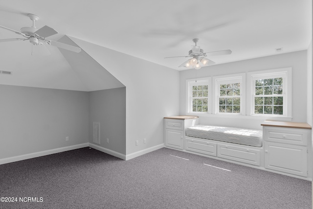 unfurnished bedroom featuring visible vents, a ceiling fan, dark carpet, baseboards, and vaulted ceiling