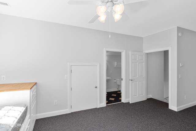 unfurnished bedroom with visible vents, baseboards, a ceiling fan, and dark carpet