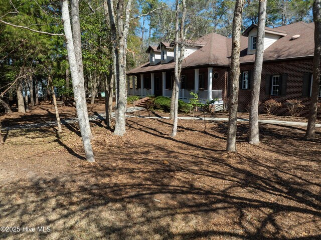 back of house featuring a porch and brick siding