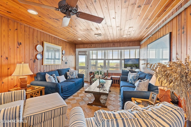 carpeted living room with wood ceiling, ceiling fan, and wooden walls