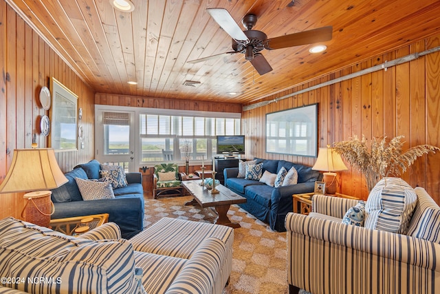 living room featuring ceiling fan, light colored carpet, wood ceiling, and wooden walls