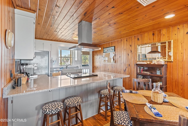 kitchen with white cabinetry, island range hood, wooden ceiling, black electric cooktop, and kitchen peninsula