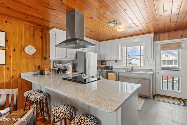 kitchen with high end fridge, extractor fan, kitchen peninsula, and wood walls