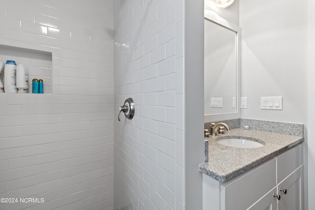 bathroom featuring a tile shower and vanity