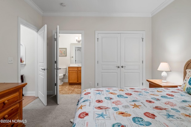 carpeted bedroom featuring ensuite bathroom, a closet, and ornamental molding