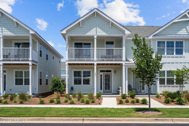 view of front facade with a balcony and a front lawn