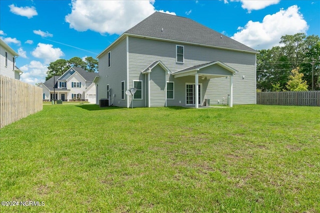 back of property featuring central AC unit and a yard