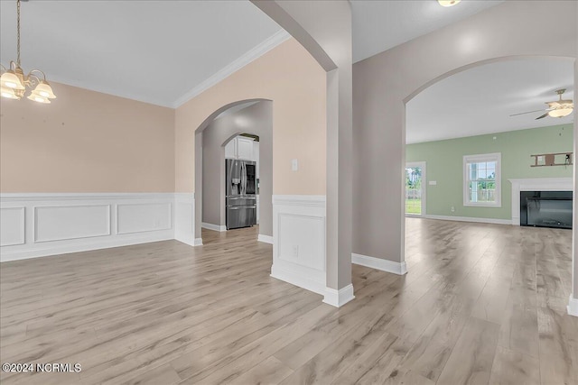 interior space featuring ceiling fan with notable chandelier, crown molding, and light wood-type flooring