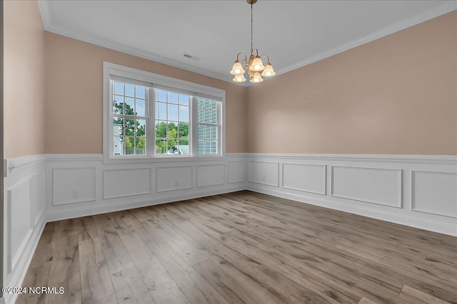 spare room featuring an inviting chandelier, light hardwood / wood-style flooring, and ornamental molding